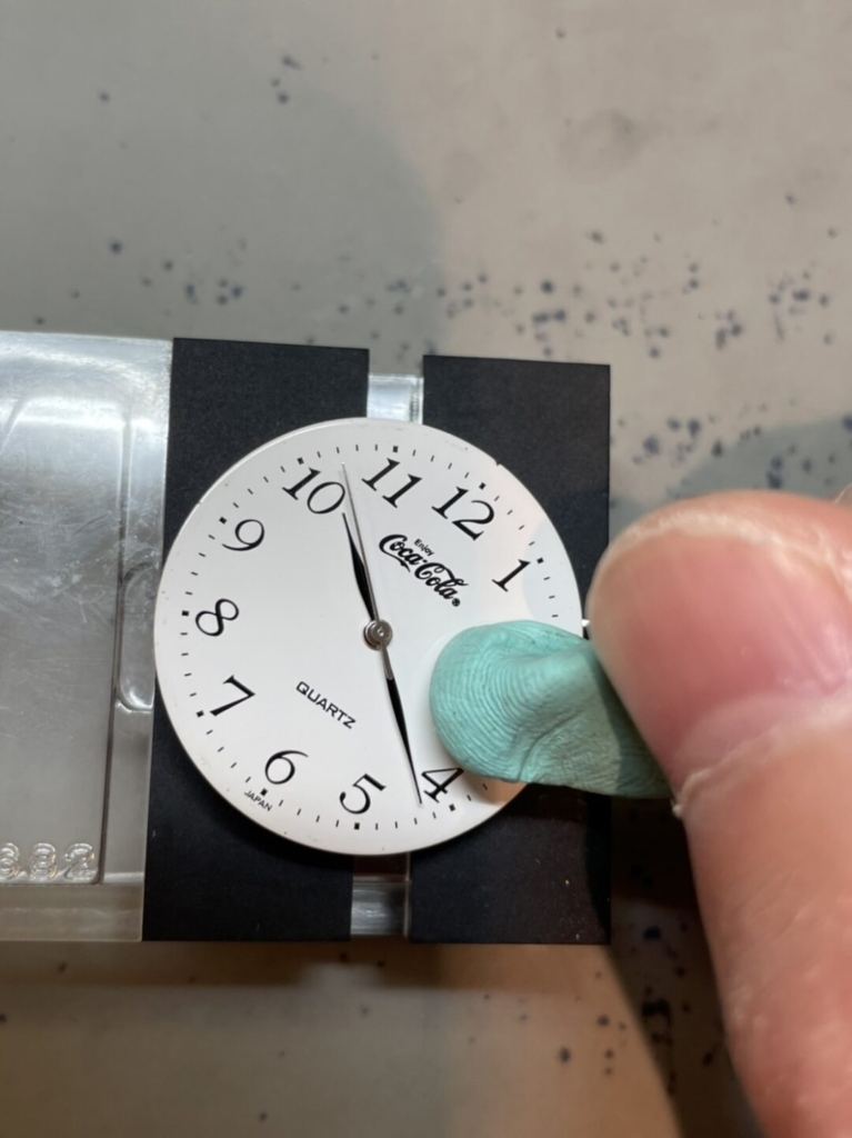 ノーブランド（コカ・コーラ）クォーツ式腕時計の取り出した文字盤をロディコを使って小さなホコリなどを取り除いていきます。ねり消しのようですね！